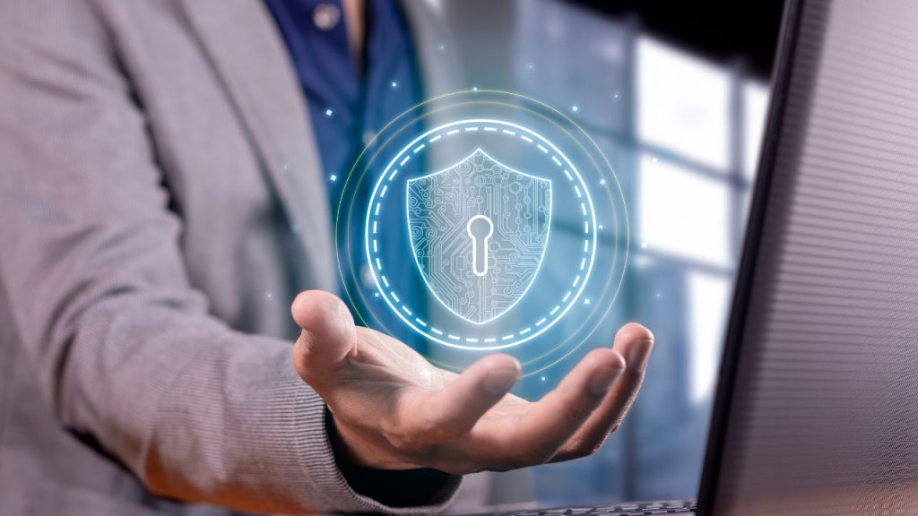 A hand holding a digital shield icon symbolizing data protection and security measures implemented by a cybersecurity architect.