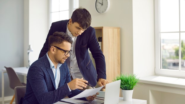 Two financial professionals analyzing data and reports on a tablet with charts and graphs, focusing on big data-driven insights for consistent financial reporting.