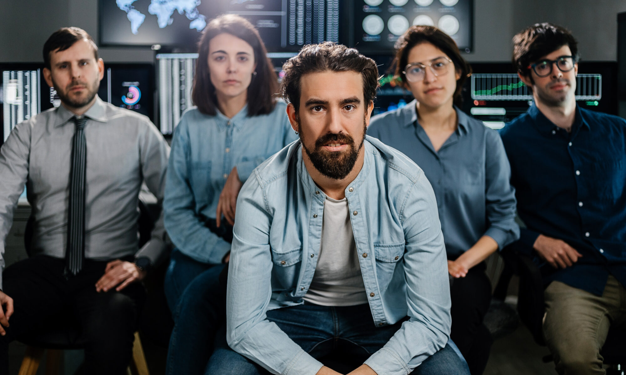 Stock trader teamwork looking at camera against multiple monitors