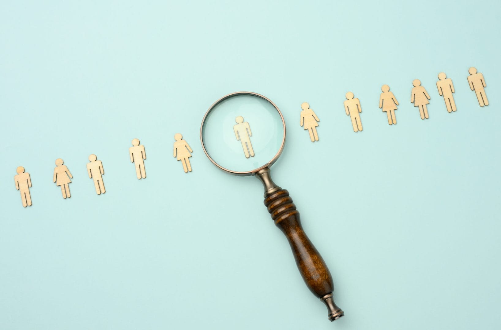 wooden men and a magnifying glass on a blue background. Recruitm
