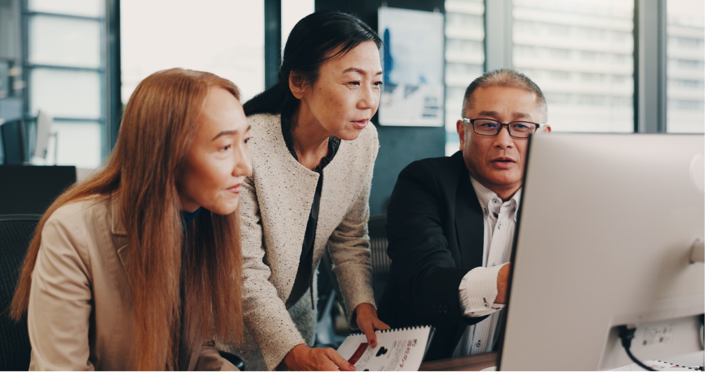 Two women and one man in front of computer